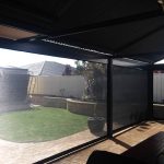 patio looking through ziptrak blinds to yard and upturned trampoline.