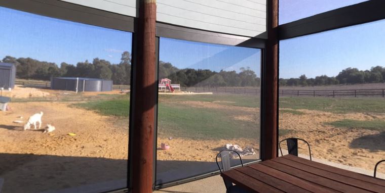looking out from outdoor dining area through ziptrak blinds.